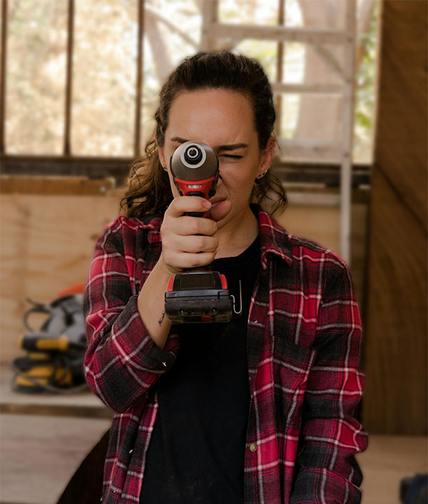 A woman holding a power tool in front of her face